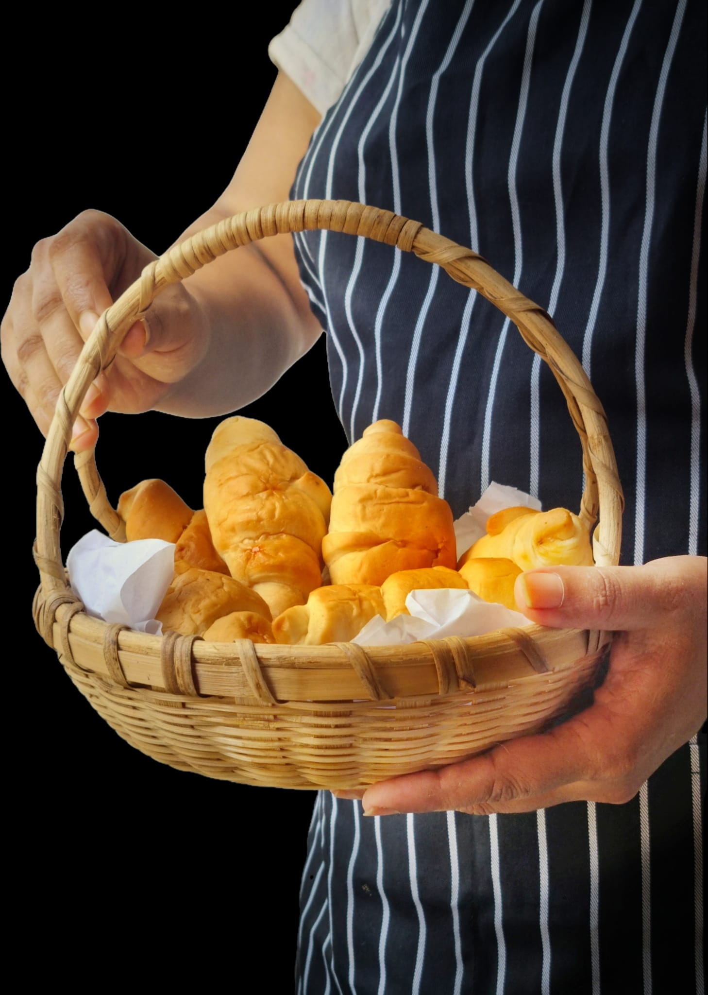 A person holding a basket with croissants